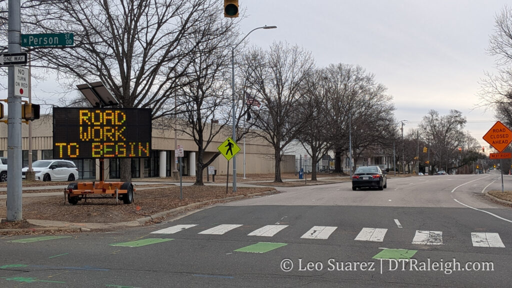 Photo of New Bern Avenue with a construction sign saying "Road Work to Begin"